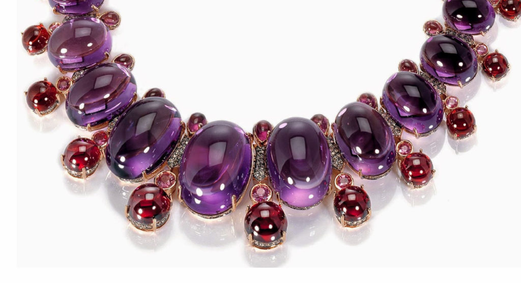A necklace featuring large oval amethyst stone alternating with smaller red stones, probably ruby.