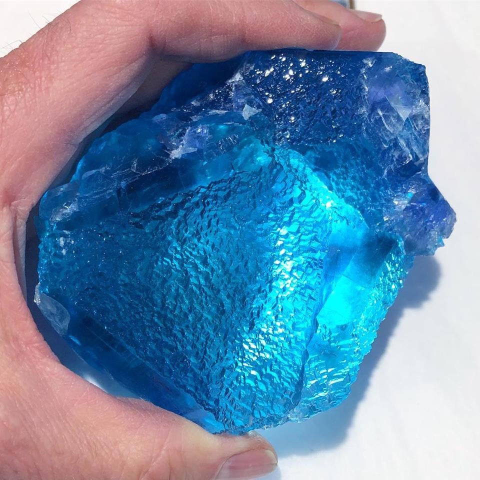 A person holds a bright blue fluorite stone.